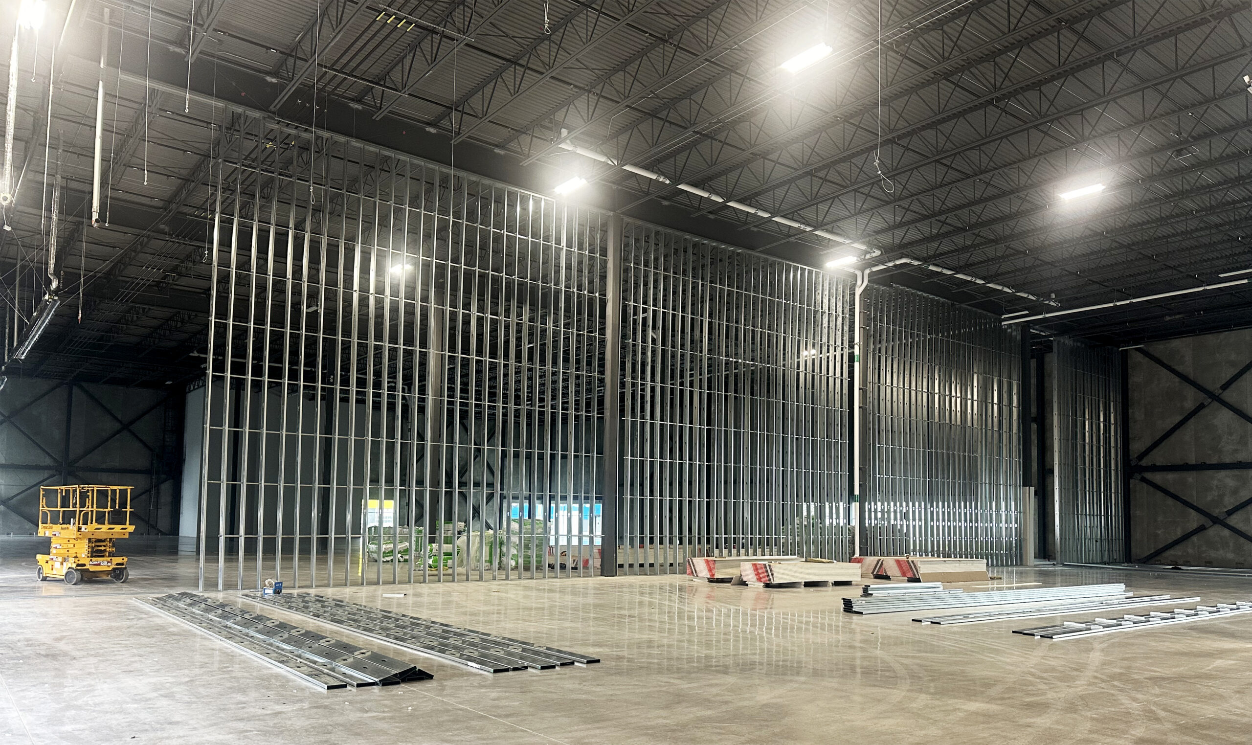 A large warehouse featuring a metal frame filled with various construction equipment, associated with Maddison Construction.